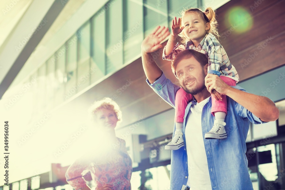 Portrait of happy family waving in arrival area at airport
