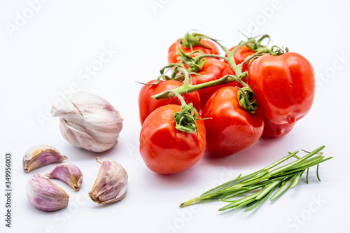 red cherry tomatoes with garlic cloves and rosemary on white background