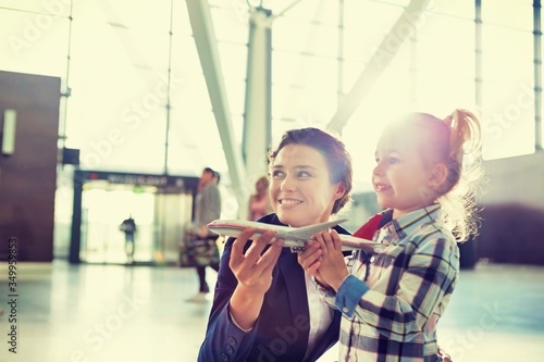 Portrait of airport staff holding airplane toy while playing with cute little girl in airport
