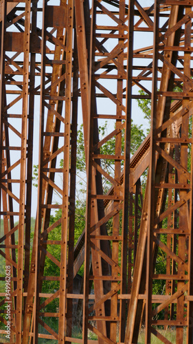 An old disused rusted brown bridge in the countryside connecting two banks across a river  formerly used for busy agricultural traffic