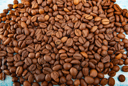 Roasted coffee grains on a blue wooden background, close-up.