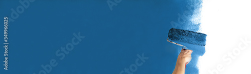 Wallpaper Mural Human hand with large roller of paint begins to paint a white wall handicraft education contrast color sample color test tool renovation dark blue maritime children's room Torontodigital.ca