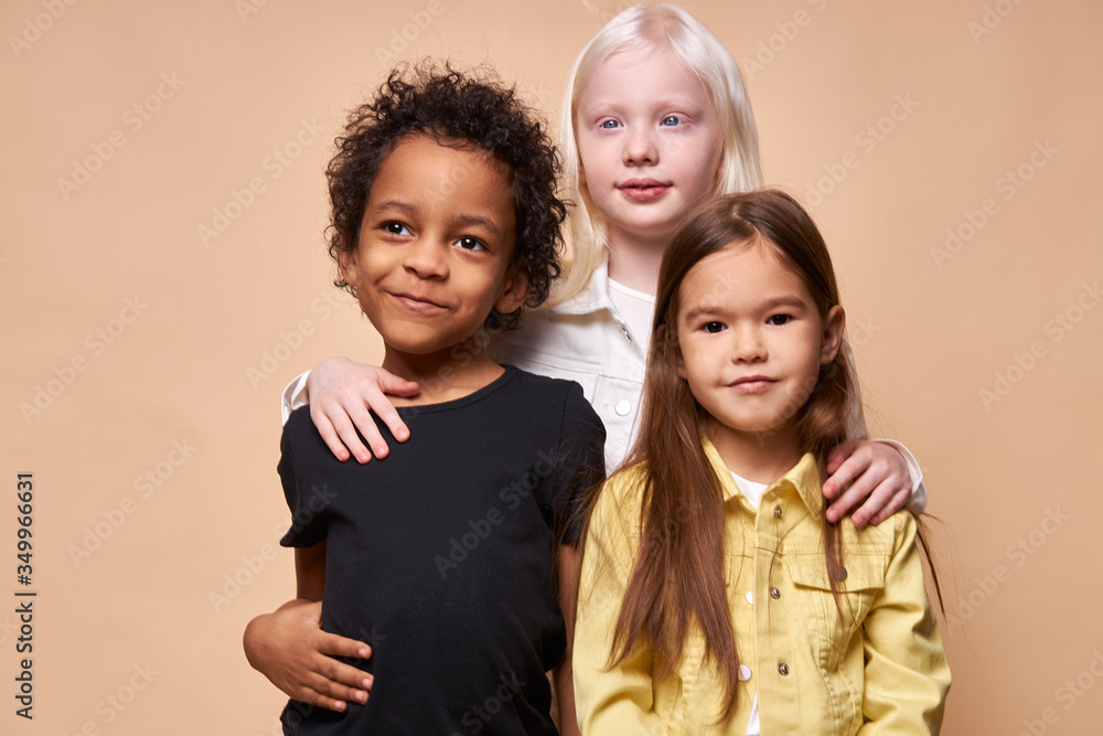 8 years old albino girl hug younger friends, africanamerican boy and caucasian girl look at camera. people diversity, unusual natural beauty concept 8 years old albino girl hug younger friends, africanamerican boy and caucasian girl look at camera. people diversity, unusual natural beauty concept