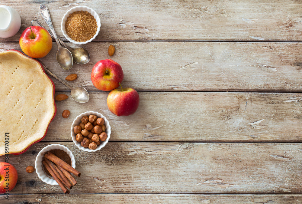 Food wooden background with cooking tray with dough, red apples and baking ingredients Food wooden background with cooking tray with dough, red apples and baking ingredients