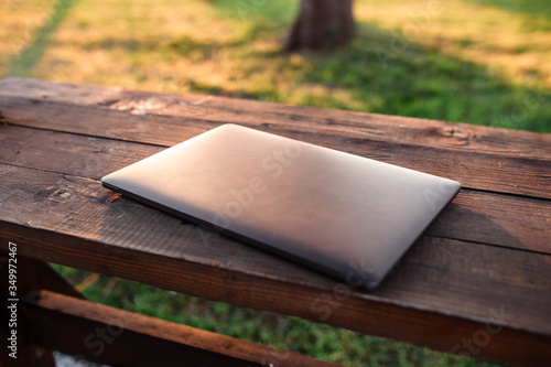 Single laptop computer on a wooden table. Laptop lying on a wooden table behind which is sunset. Laptop. Free space for your text.