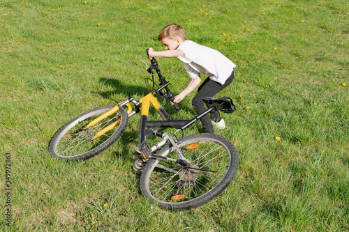 A small boy tries to lift a Bicycle