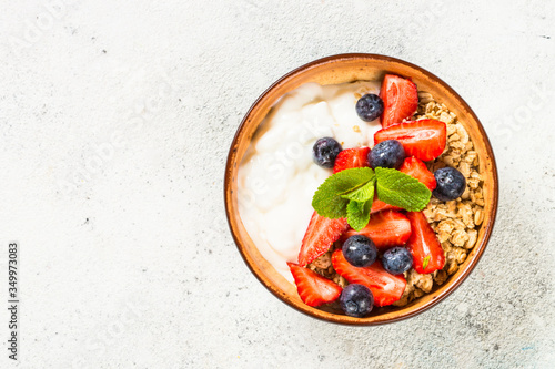 Greek yogurt granola with fresh berries on white stone table.