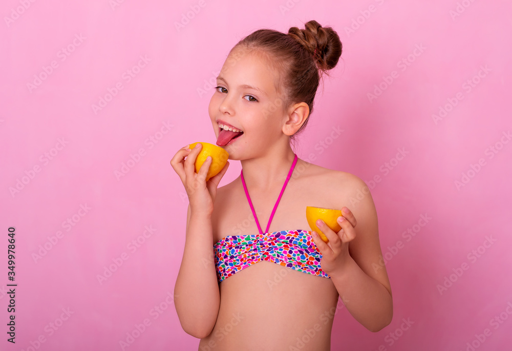 Portrait of pretty child holding slices of lemon. Girl playing with lemon. Little girl eating lemon isolated on pink background, grimacing. Girl shows tongue, has fun. Portrait of pretty child holding slices of lemon. Girl playing with lemon. Little girl eating lemon isolated on pink background, grimacing. Girl shows tongue, has fun.