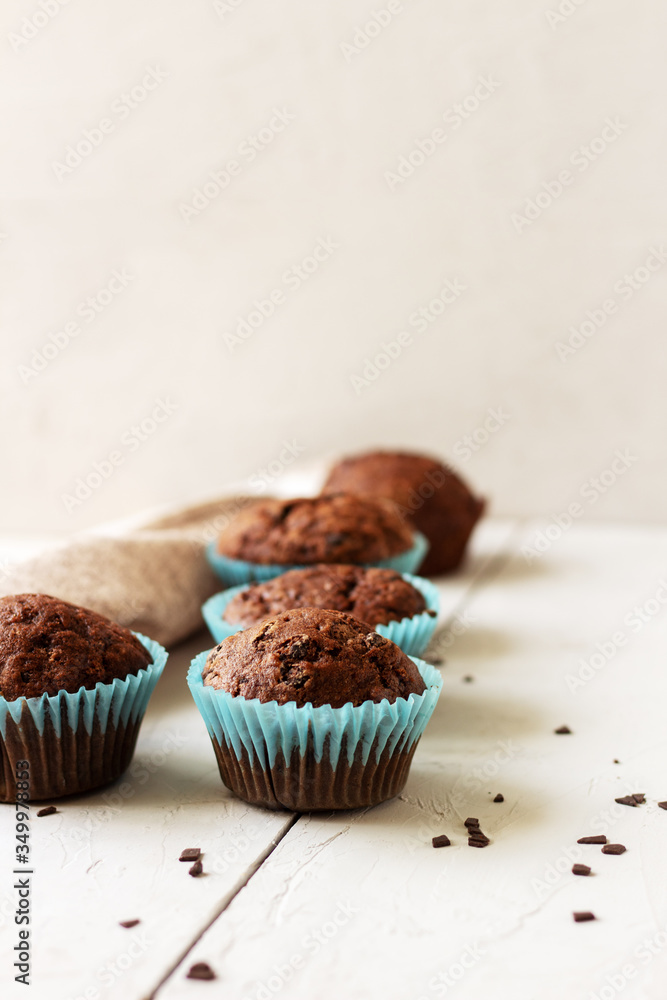 Homemade сhocolate muffins with banana in blue paper cups on white, wooden background. Homemade сhocolate muffins with banana in blue paper cups on white, wooden background.