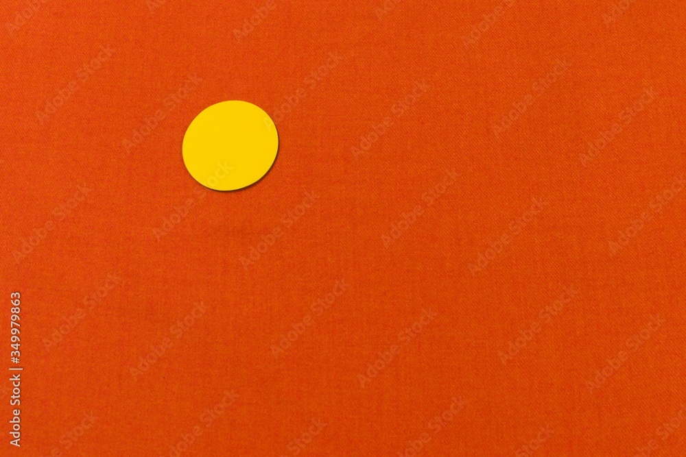 yellow cardboard circle on an orange wool fabric yellow cardboard circle on an orange wool fabric