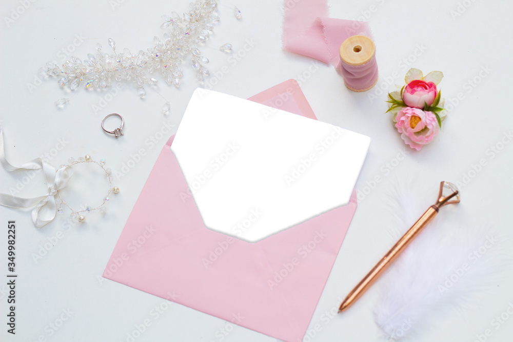 White blank paper in pink envelope on white background and bridal themed accessories around White blank paper in pink envelope on white background and bridal themed accessories around