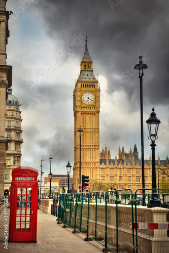 Traditional red phone booth and Big Ben in London at cloudy day