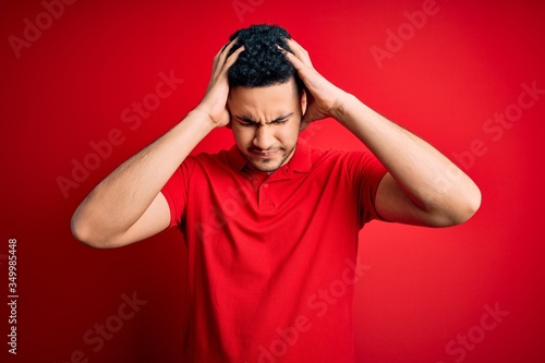 Fotografie Young handsome man wearing red casual polo standing over isolated background suffering from headache desperate and stressed because pain and migraine