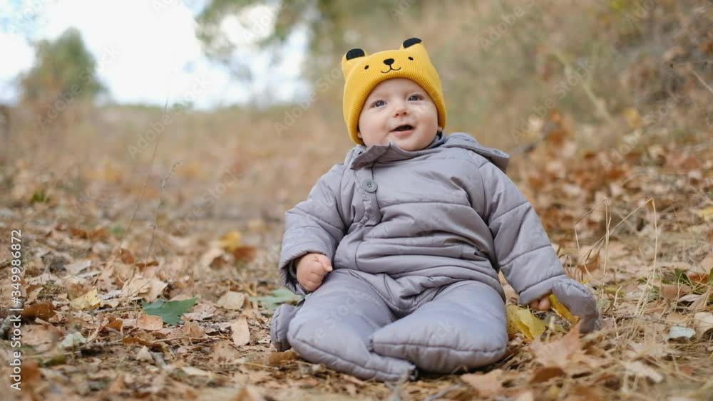 Toddler sits in yellow leaves in the park in the fall. Autumn walk with the baby. Acquaintance of the kid with yellow autumn leaves. Toddler sits in yellow leaves in the park in the fall. Autumn walk with the baby. Acquaintance of the kid with yellow autumn leaves.