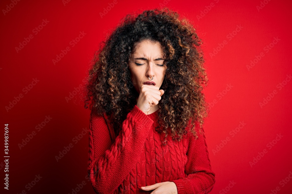 Young beautiful woman with curly hair and piercing wearing casual red sweater feeling unwell and coughing as symptom for cold or bronchitis. Health care concept. Young beautiful woman with curly hair and piercing wearing casual red sweater feeling unwell and coughing as symptom for cold or bronchitis. Health care concept.