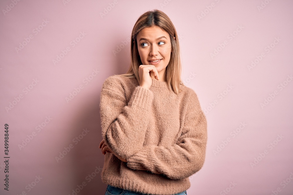 Young beautiful blonde woman wearing winter wool sweater over pink isolated background with hand on chin thinking about question, pensive expression. Smiling and thoughtful face. Doubt concept. Young beautiful blonde woman wearing winter wool sweater over pink isolated background with hand on chin thinking about question, pensive expression. Smiling and thoughtful face. Doubt concept.