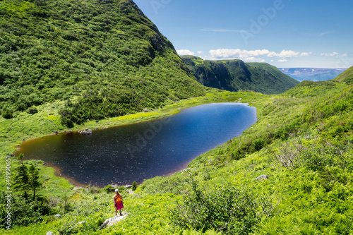 Woman hiking down to small mountain lake photo