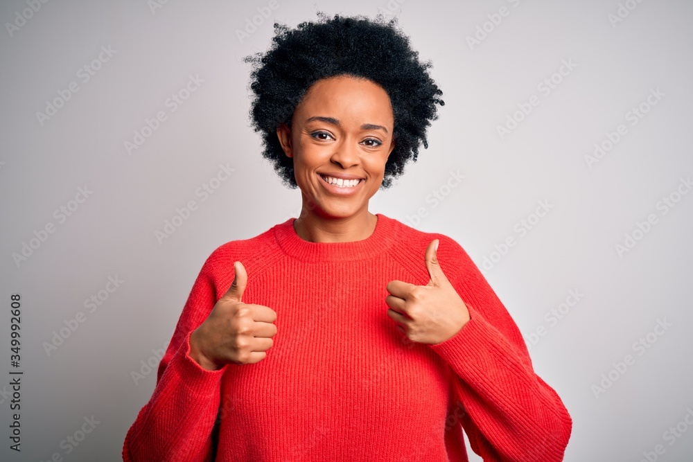 Young beautiful African American afro woman with curly hair wearing red casual sweater success sign doing positive gesture with hand, thumbs up smiling and happy. Cheerful expression and winner Young beautiful African American afro woman with curly hair wearing red casual sweater success sign doing positive gesture with hand, thumbs up smiling and happy. Cheerful expression and winner