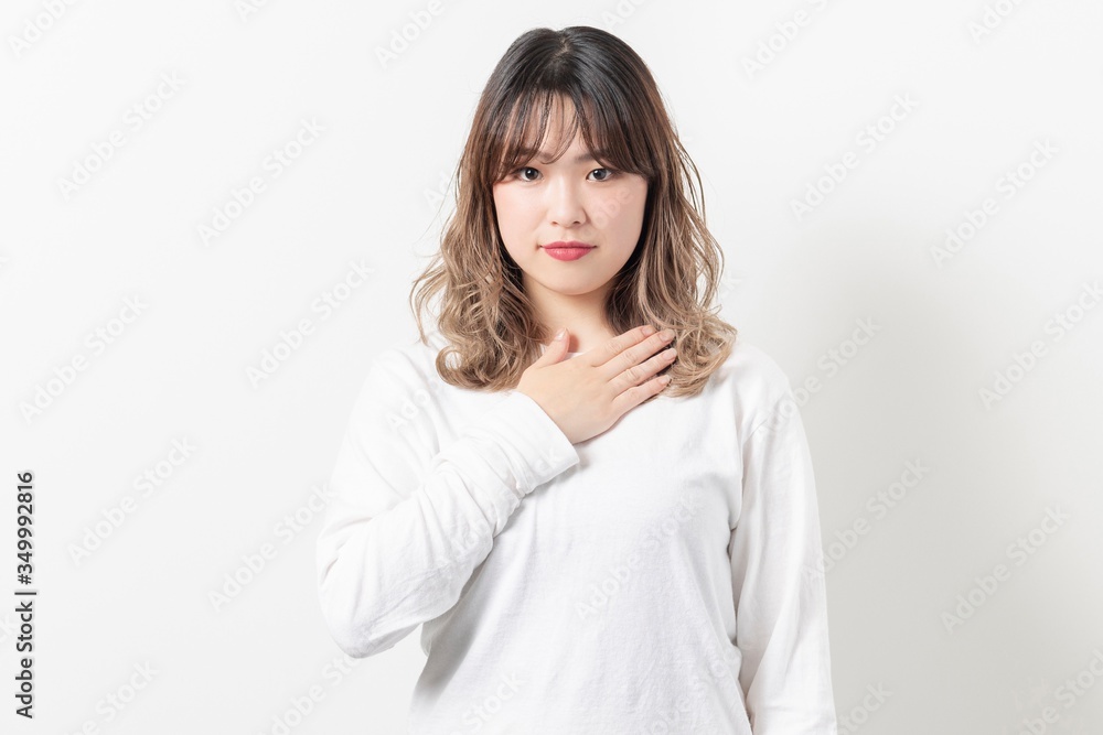 胸に手を当てる若い女性 胸に手を当てる若い女性