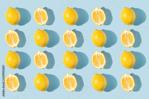 Fototapeta Naklejka Na Ścianę i Meble -  Pattern of lemons with shadow on a blue background. Fresh bright fruits, vitamins. Healthy eating concept. Halves of lemons. complementary colors.