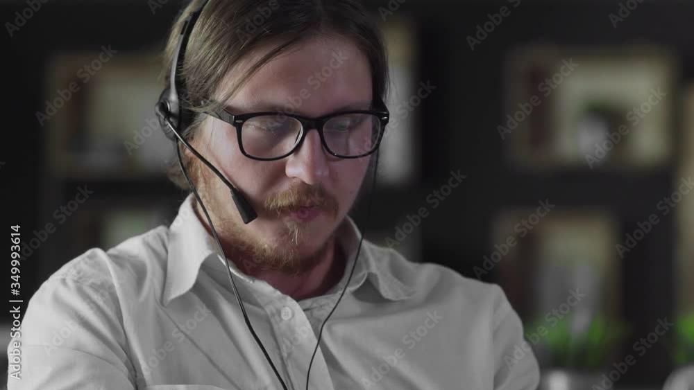 Manager in headphones is working at desk in office alone Manager in headphones is working at desk in office alone