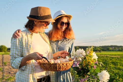 Portrait of two embraced women mother and daughter with basket of eggs