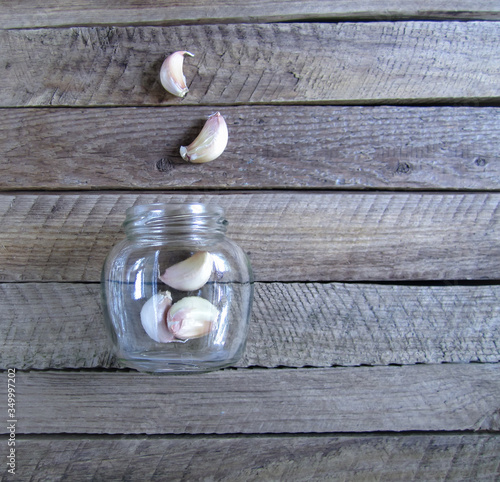Rough wooden vintage natural texrured background with copy space and cloves of garlic in a glass jar photo