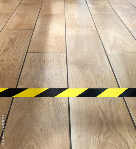 yellow-black striped tape glued on the floor with wood-like tiles to separate zones or set borders