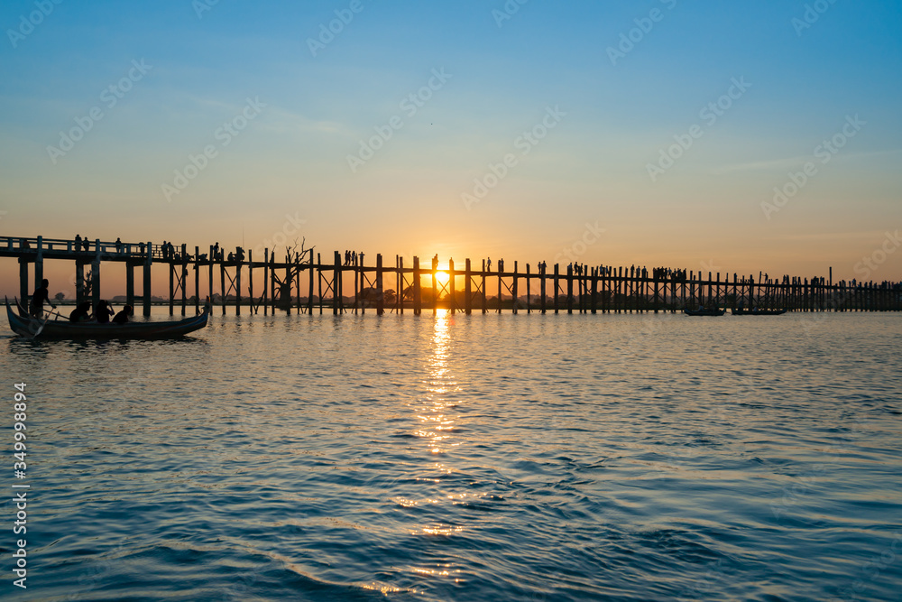 .U Bein Bridge crosses Taungthaman Lake near Amarapura in silhouette as sun sets behind .U Bein Bridge crosses Taungthaman Lake near Amarapura in silhouette as sun sets behind
