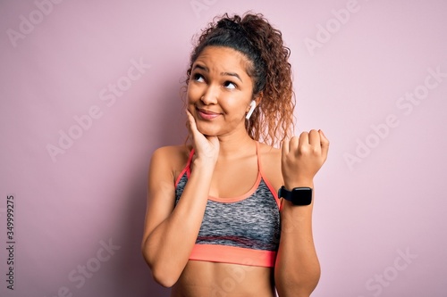 Beautiful sportswoman with curly hair doing sport wearing sportswear using smartwatch serious face thinking about question, very confused idea © Krakenimages.com