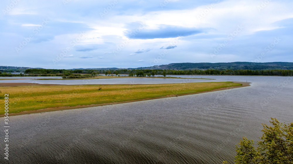 Piaszczyste wyspy na jeziorze, porośnięte drzewami w słoneczny dzień 