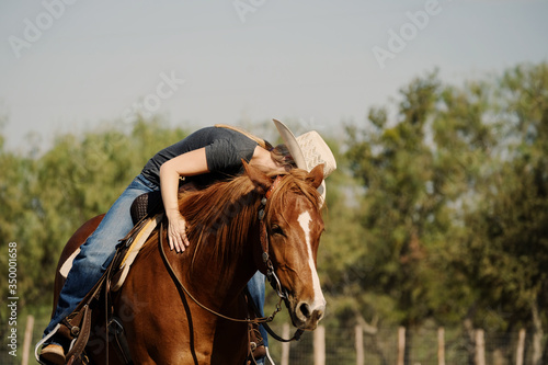 Western lifestyle shows cowgirl loving on horse while riding close up.