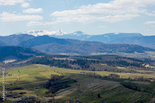 View of the Carpathian Mountains landscape in cloudy summer day. Mountain peaks, forests, fields and meadows, beautiful natural landscape