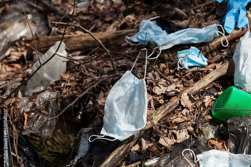 Used face masks and gloves are thrown into the garbage dump along with plastic containers and plastic bags. Pollution of nature by new types of waste resulting from the epidemic of coronavirus photo