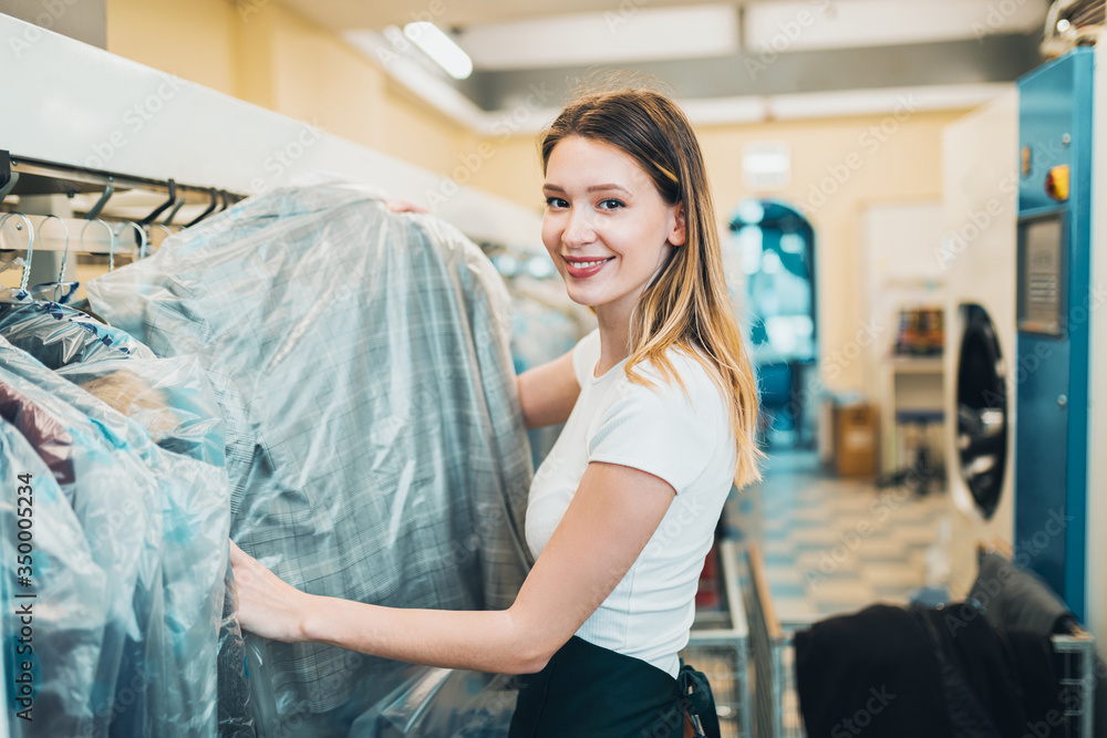 Obraz premium Young female worker in dry-cleaning salon.
