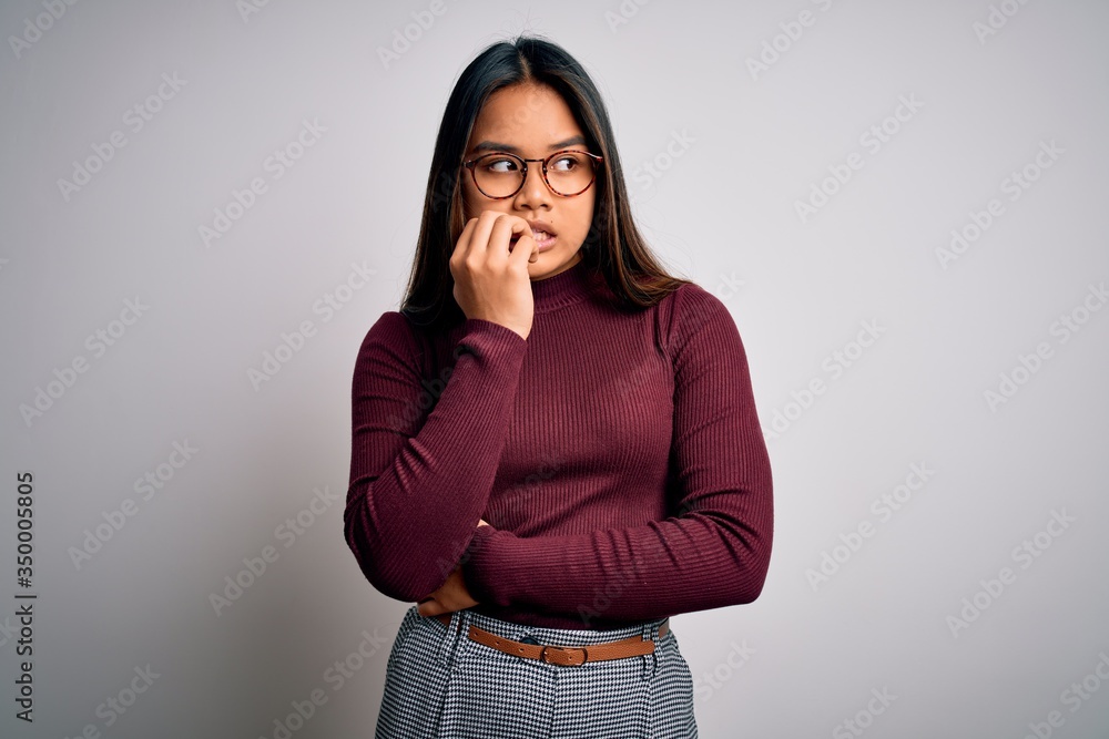 Beautiful asian business woman wearing casual sweater and glasses over white background looking stressed and nervous with hands on mouth biting nails. Anxiety problem. Beautiful asian business woman wearing casual sweater and glasses over white background looking stressed and nervous with hands on mouth biting nails. Anxiety problem.
