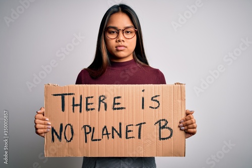 Young asian activist girl asking for environment holding banner with planet message with a confident expression on smart face thinking serious © Krakenimages.com