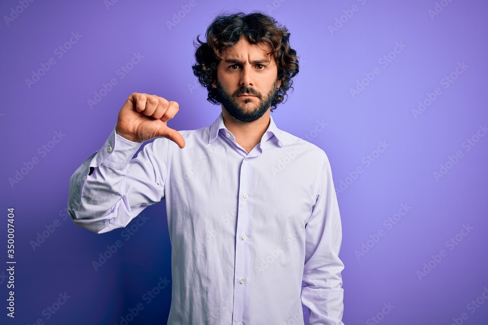 Fototapeta premium Young handsome business man with beard wearing shirt standing over purple background looking unhappy and angry showing rejection and negative with thumbs down gesture. Bad expression.