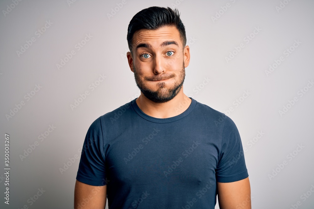 Young handsome man wearing casual t-shirt standing over isolated white background puffing cheeks with funny face. Mouth inflated with air, crazy expression.