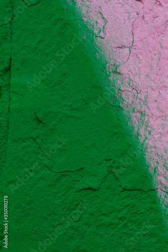 The old shabby wall is painted with green and pink spray paint. Pink paint forms an irregular triangle. There is a place for text. Vertical photo was shot for your design.