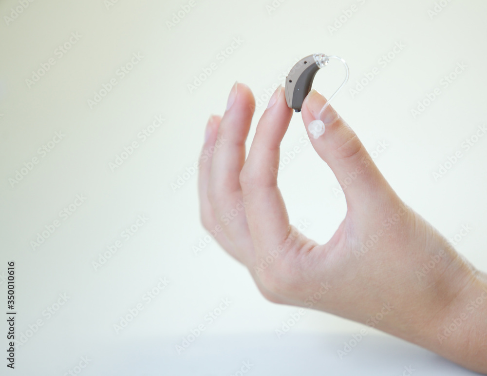 Very small hearing aid in a female hand Very small hearing aid in a female hand