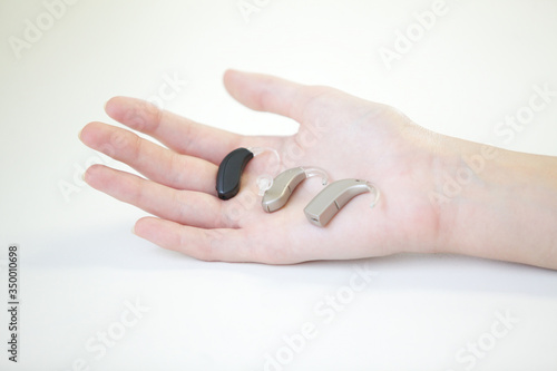 Three hearing aids in a female hand