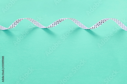Silk white ribbon for gift on bright green background.