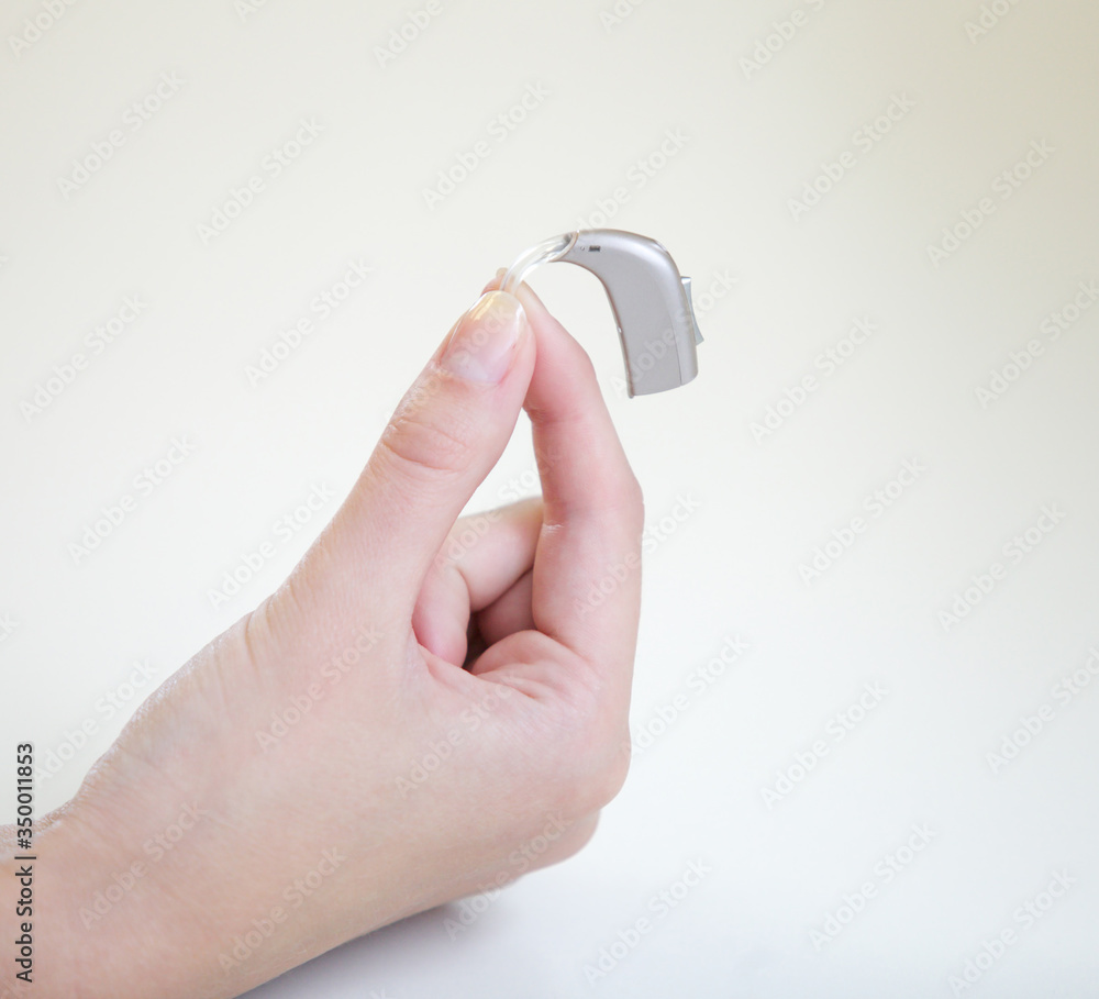 Very small hearing aid in a female hand Very small hearing aid in a female hand