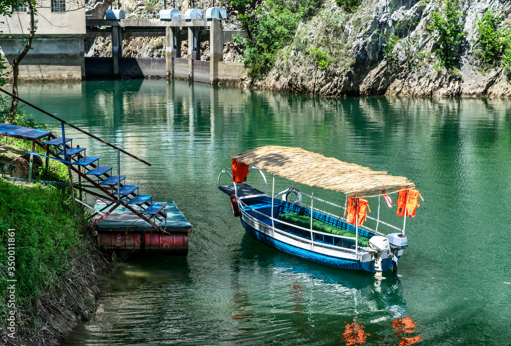 Obraz premium Small tourists transportation Blue boat docked in the small bay at Matka Canyon, Skopje, Macedonia