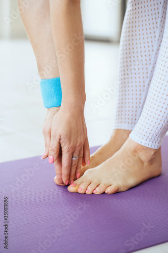 Woman's hands and feet on yoga mat close up picture. Female doing exercise indoors at home.