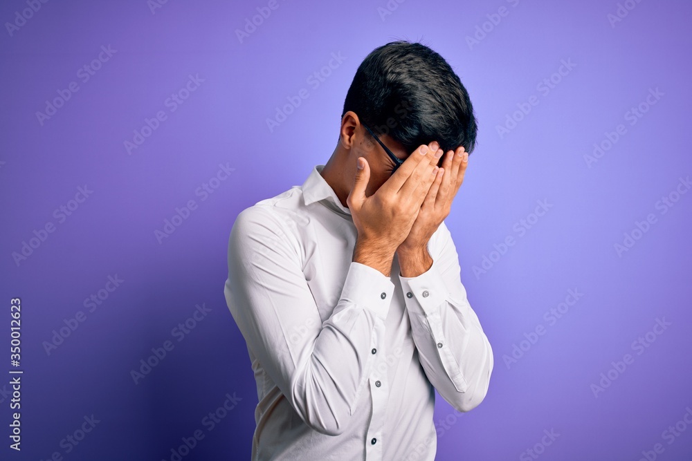Young handsome business man wearing shirt and glasses over isolated purple background with sad expression covering face with hands while crying. Depression concept. Young handsome business man wearing shirt and glasses over isolated purple background with sad expression covering face with hands while crying. Depression concept.