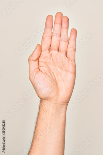 Hand of caucasian young man showing fingers over isolated white background stretching and reaching with open hand for handshake  showing palm