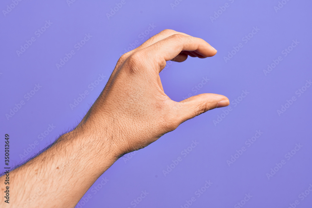 Hand of caucasian young man showing fingers over isolated purple background picking and taking invisible thing, holding object with fingers showing space Hand of caucasian young man showing fingers over isolated purple background picking and taking invisible thing, holding object with fingers showing space