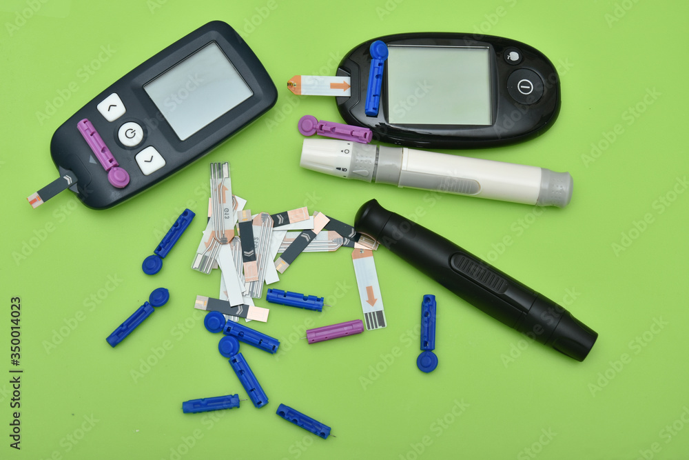 2 glucometer, lancet, spare needles on green background 2 glucometer, lancet, spare needles on green background